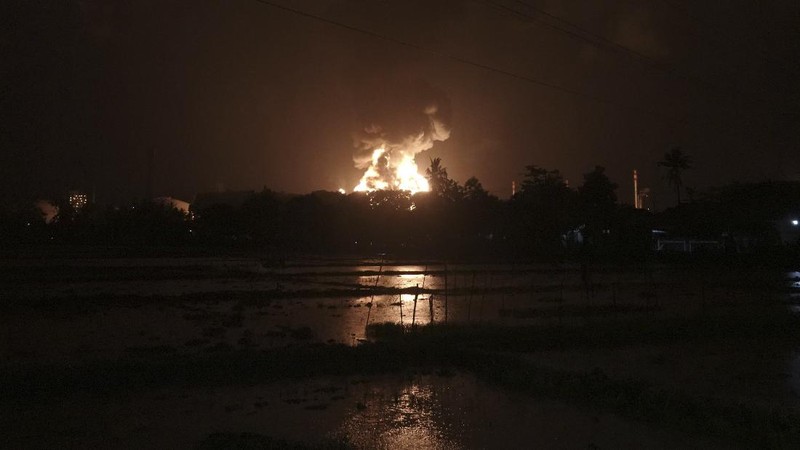 The sky glows from the fire that razes through an oil refinery owned by the national oil company Pertamina, in Cilacap, Central Java, Indonesia, Saturday, Nov. 13, 2021. The fire at a gasoline storage at the largest oil refinery on Indonesia's Java island prompted the evacuation of dozens of residents living nearby. (AP Photo/Agus Fitrah)