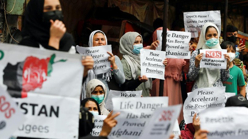 Afghan women and children refugees living in Indonesia hold posters during a rally outside a building that houses UNHCR representative office in Jakarta, Indonesia, Monday, Nov. 15, 2021. Hundreds of Afghan refugees and asylum seekers living in Indonesia rallied in front of the U.N. refugee agency office in Jakarta on Monday to urge it to speed up their resettlement.(AP Photo/Achmad Ibrahim)