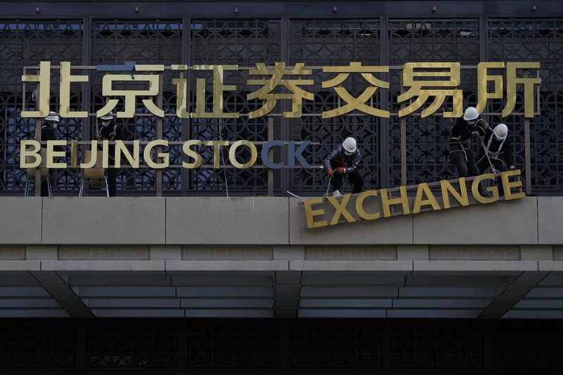 Men are seen near the new Beijing Stock Exchange building at the Financial Street, in Beijing, China, November 15, 2021. REUTERS/Tingshu Wang