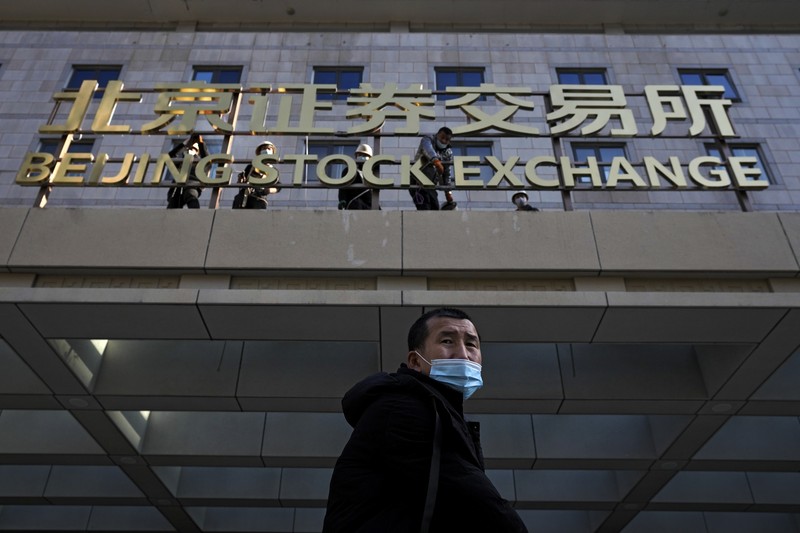 Men are seen near the new Beijing Stock Exchange building at the Financial Street, in Beijing, China, November 15, 2021. REUTERS/Tingshu Wang
