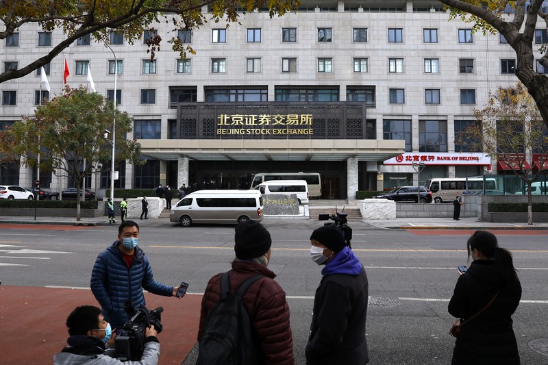 Men are seen near the new Beijing Stock Exchange building at the Financial Street, in Beijing, China, November 15, 2021. REUTERS/Tingshu Wang