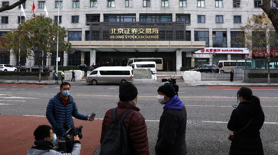 Men are seen near the new Beijing Stock Exchange building at the Financial Street, in Beijing, China, November 15, 2021. REUTERS/Tingshu Wang