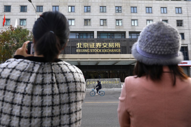 Men are seen near the new Beijing Stock Exchange building at the Financial Street, in Beijing, China, November 15, 2021. REUTERS/Tingshu Wang