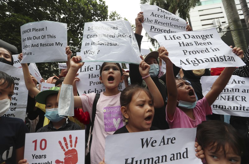 Indonesia Afghan Refugees Afghan women and children refugees living in Indonesia hold posters during a rally outside a building that houses UNHCR representative office in Jakarta, Indonesia, Monday, Nov. 15, 2021. Hundreds of Afghan refugees and asylum seekers living in Indonesia rallied in front of the U.N. refugee agency office in Jakarta on Monday to urge it to speed up their resettlement.(AP Photo/Achmad Ibrahim)