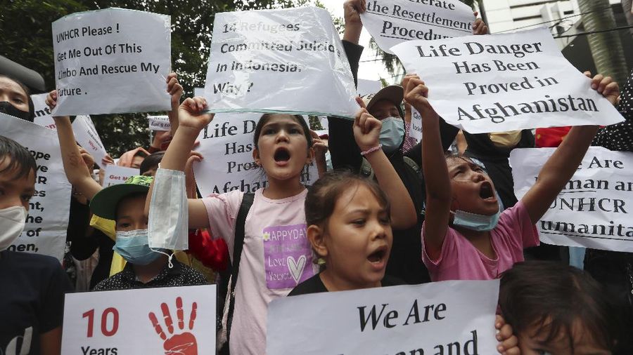 Afghan women and children refugees living in Indonesia hold posters during a rally outside a building that houses UNHCR representative office in Jakarta, Indonesia, Monday, Nov. 15, 2021. Hundreds of Afghan refugees and asylum seekers living in Indonesia rallied in front of the U.N. refugee agency office in Jakarta on Monday to urge it to speed up their resettlement.(AP Photo/Achmad Ibrahim)