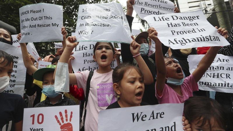 Afghan women and children refugees living in Indonesia hold posters during a rally outside a building that houses UNHCR representative office in Jakarta, Indonesia, Monday, Nov. 15, 2021. Hundreds of Afghan refugees and asylum seekers living in Indonesia rallied in front of the U.N. refugee agency office in Jakarta on Monday to urge it to speed up their resettlement.(AP Photo/Achmad Ibrahim)