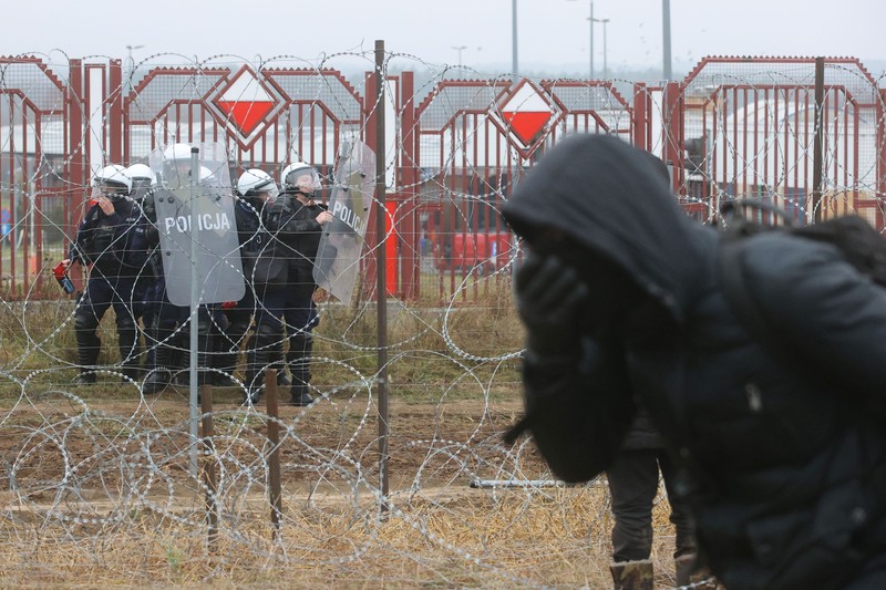 EUROPE-MIGRANTS/BELARUS-POLAND Polish law enforcement officers use water cannons, as migrants carry a log towards a fence at Kuznica - Bruzgi checkpoint, Poland, November 16, 2021. Policja Podlaska/Handout via REUTERS NO RESALES. NO ARCHIVES. MANDATORY CREDIT. THIS IMAGE HAS BEEN SUPPLIED BY A THIRD PARTY.