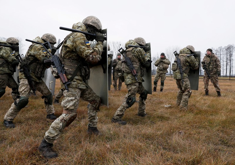 Polish law enforcement officers use water cannons, as migrants carry a log towards a fence at Kuznica - Bruzgi checkpoint, Poland, November 16, 2021. Policja Podlaska/Handout via REUTERS NO RESALES. NO ARCHIVES. MANDATORY CREDIT. THIS IMAGE HAS BEEN SUPPLIED BY A THIRD PARTY.