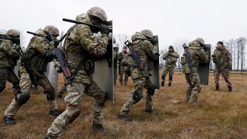 Polish law enforcement officers use water cannons, as migrants carry a log towards a fence at Kuznica - Bruzgi checkpoint, Poland, November 16, 2021. Policja Podlaska/Handout via REUTERS NO RESALES. NO ARCHIVES. MANDATORY CREDIT. THIS IMAGE HAS BEEN SUPPLIED BY A THIRD PARTY.