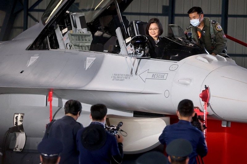 A Taiwanese Air Force flag bearer passes by one of the newly commissioned upgraded F-16V fighter jets at Air Force base in Chiayi in southwestern Taiwan Thursday, Nov. 18, 2021. Taiwan has deployed the most advanced version of the F-16 fighter jet in its Air Force, as the island steps up its defense capabilities in the face of continuing threats from China. (AP Photo/Johnson Lai)