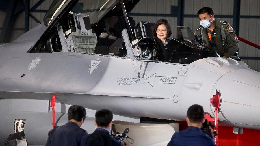 A Taiwanese Air Force flag bearer passes by one of the newly commissioned upgraded F-16V fighter jets at Air Force base in Chiayi in southwestern Taiwan Thursday, Nov. 18, 2021. Taiwan has deployed the most advanced version of the F-16 fighter jet in its Air Force, as the island steps up its defense capabilities in the face of continuing threats from China. (AP Photo/Johnson Lai)