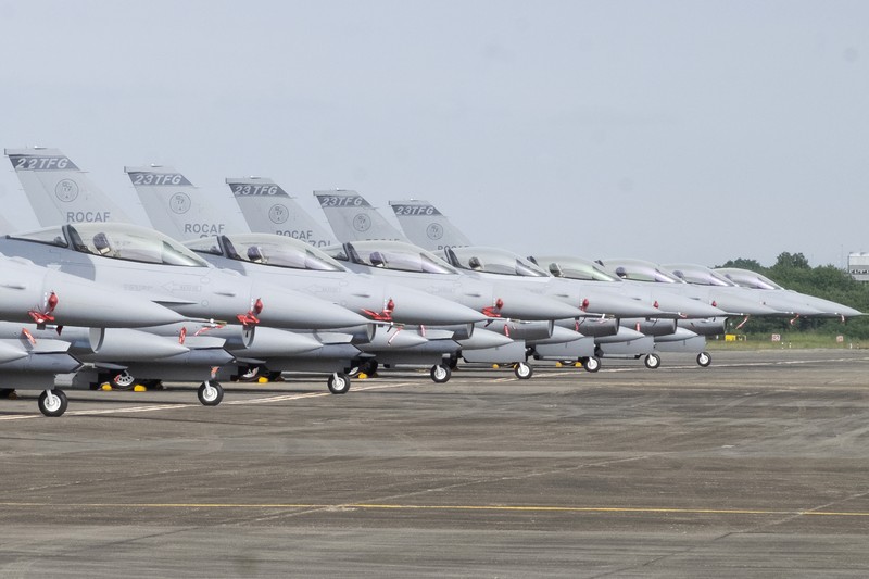 A Taiwanese Air Force flag bearer passes by one of the newly commissioned upgraded F-16V fighter jets at Air Force base in Chiayi in southwestern Taiwan Thursday, Nov. 18, 2021. Taiwan has deployed the most advanced version of the F-16 fighter jet in its Air Force, as the island steps up its defense capabilities in the face of continuing threats from China. (AP Photo/Johnson Lai)