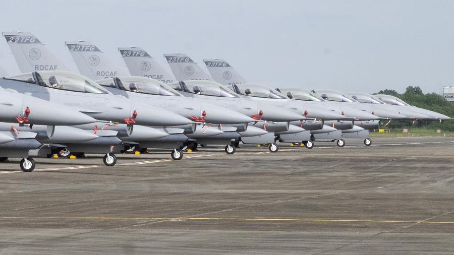 A Taiwanese Air Force flag bearer passes by one of the newly commissioned upgraded F-16V fighter jets at Air Force base in Chiayi in southwestern Taiwan Thursday, Nov. 18, 2021. Taiwan has deployed the most advanced version of the F-16 fighter jet in its Air Force, as the island steps up its defense capabilities in the face of continuing threats from China. (AP Photo/Johnson Lai)