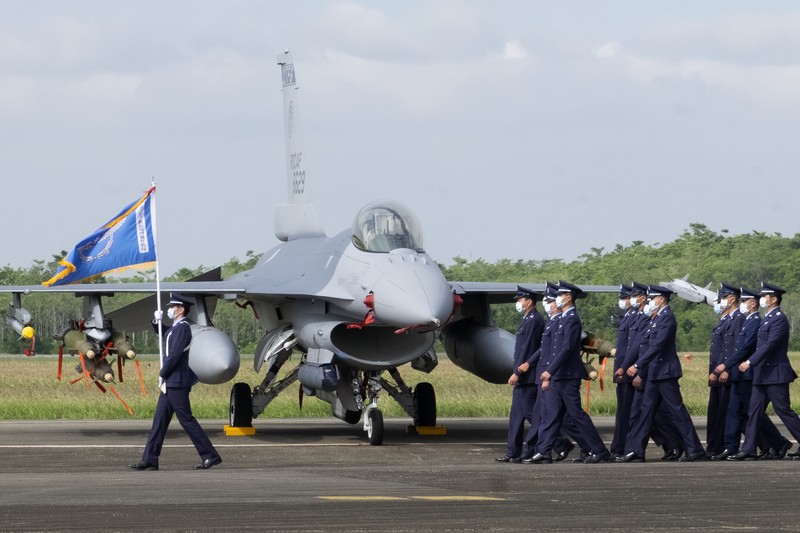 A Taiwanese Air Force flag bearer passes by one of the newly commissioned upgraded F-16V fighter jets at Air Force base in Chiayi in southwestern Taiwan Thursday, Nov. 18, 2021. Taiwan has deployed the most advanced version of the F-16 fighter jet in its Air Force, as the island steps up its defense capabilities in the face of continuing threats from China. (AP Photo/Johnson Lai)
