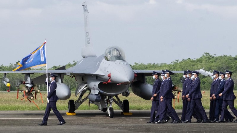 A Taiwanese Air Force flag bearer passes by one of the newly commissioned upgraded F-16V fighter jets at Air Force base in Chiayi in southwestern Taiwan Thursday, Nov. 18, 2021. Taiwan has deployed the most advanced version of the F-16 fighter jet in its Air Force, as the island steps up its defense capabilities in the face of continuing threats from China. (AP Photo/Johnson Lai)