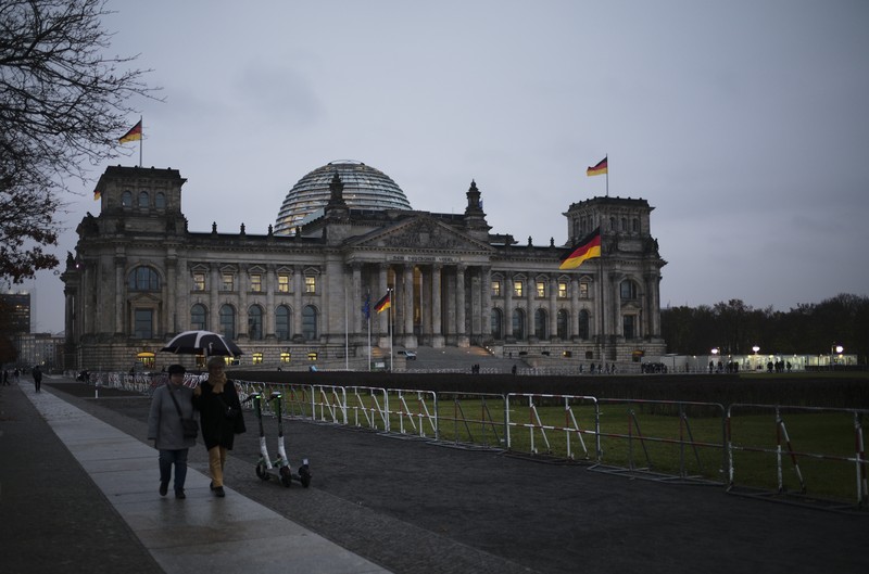 People jogging in front of the Reichstag building with the German parliament Bundestag in Berlin, Germany, Wednesday, Nov. 17, 2021. In its session on Thursday Nov. 18, 2021, the Bundestag wants to vote on new measures to battle the fourth wave of the coronavirus pandemic.(AP Photo/Markus Schreiber)