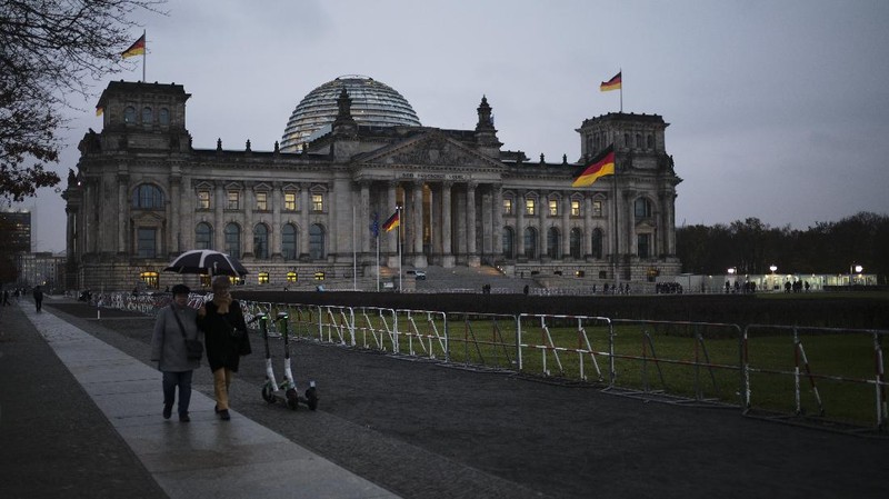 People jogging in front of the Reichstag building with the German parliament Bundestag in Berlin, Germany, Wednesday, Nov. 17, 2021. In its session on Thursday Nov. 18, 2021, the Bundestag wants to vote on new measures to battle the fourth wave of the coronavirus pandemic.(AP Photo/Markus Schreiber)