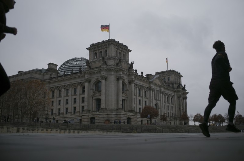People jogging in front of the Reichstag building with the German parliament Bundestag in Berlin, Germany, Wednesday, Nov. 17, 2021. In its session on Thursday Nov. 18, 2021, the Bundestag wants to vote on new measures to battle the fourth wave of the coronavirus pandemic.(AP Photo/Markus Schreiber)