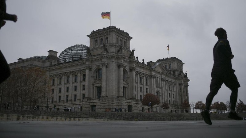 People jogging in front of the Reichstag building with the German parliament Bundestag in Berlin, Germany, Wednesday, Nov. 17, 2021. In its session on Thursday Nov. 18, 2021, the Bundestag wants to vote on new measures to battle the fourth wave of the coronavirus pandemic.(AP Photo/Markus Schreiber)