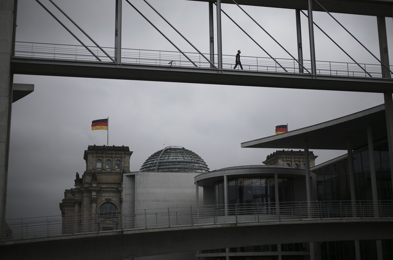 People jogging in front of the Reichstag building with the German parliament Bundestag in Berlin, Germany, Wednesday, Nov. 17, 2021. In its session on Thursday Nov. 18, 2021, the Bundestag wants to vote on new measures to battle the fourth wave of the coronavirus pandemic.(AP Photo/Markus Schreiber)