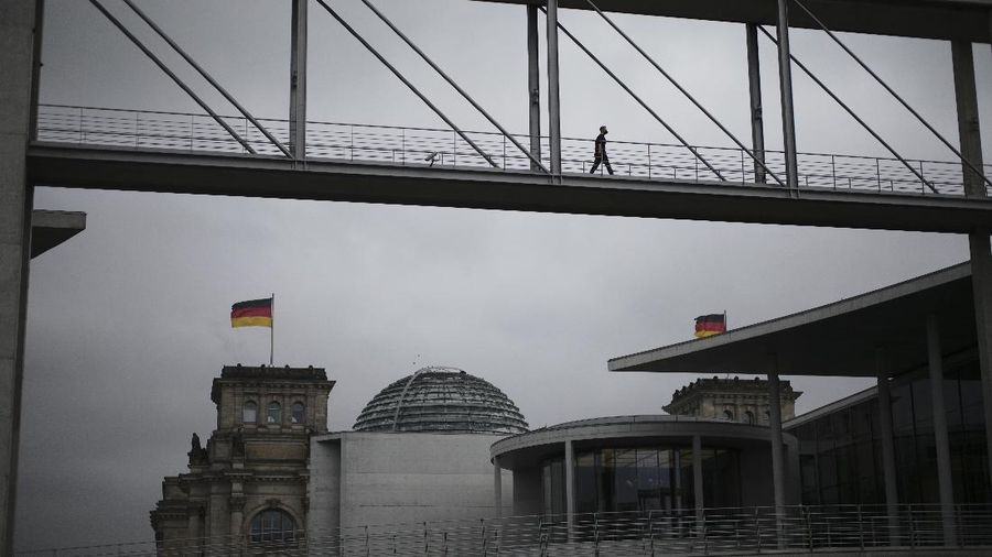 People jogging in front of the Reichstag building with the German parliament Bundestag in Berlin, Germany, Wednesday, Nov. 17, 2021. In its session on Thursday Nov. 18, 2021, the Bundestag wants to vote on new measures to battle the fourth wave of the coronavirus pandemic.(AP Photo/Markus Schreiber)