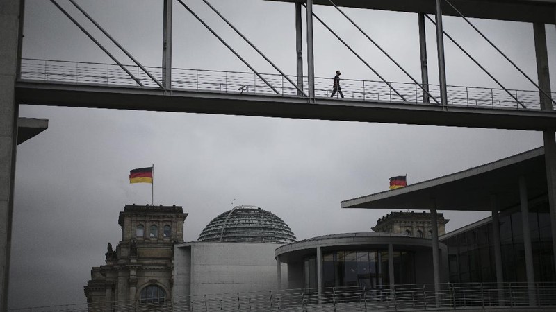 People jogging in front of the Reichstag building with the German parliament Bundestag in Berlin, Germany, Wednesday, Nov. 17, 2021. In its session on Thursday Nov. 18, 2021, the Bundestag wants to vote on new measures to battle the fourth wave of the coronavirus pandemic.(AP Photo/Markus Schreiber)