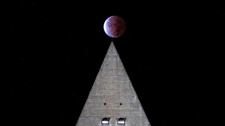 Orang-orang menyaksikan gerhana bulan parsial di atas Catania di Piazza Universita, Italia (19/11/2021). (REUTERS/Antonio Parrinello)