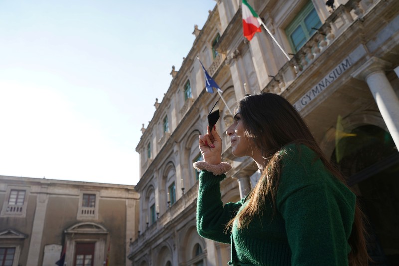 Orang-orang menyaksikan gerhana bulan parsial di atas Catania di Piazza Universita, Italia (19/11/2021). (REUTERS/Antonio Parrinello)