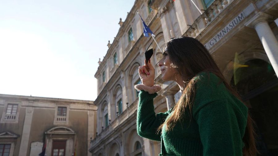Orang-orang menyaksikan gerhana bulan parsial di atas Catania di Piazza Universita, Italia (19/11/2021). (REUTERS/Antonio Parrinello)