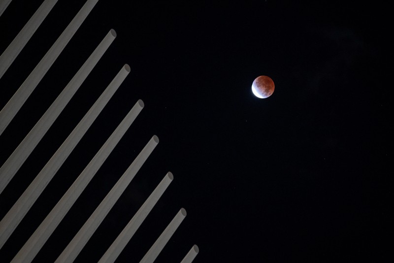 Gerhana bulan parsial atau Bulan darah di atas Catania di Piazza Universita, Italia Orang-orang menyaksikan gerhana bulan parsial di atas Catania di Piazza Universita, Italia (19/11/2021). (REUTERS/Antonio Parrinello)