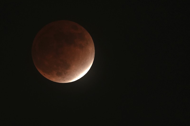 Gerhana bulan parsial atau Bulan darah di atas Catania di Piazza Universita, Italia Orang-orang menyaksikan gerhana bulan parsial di atas Catania di Piazza Universita, Italia (19/11/2021). (REUTERS/Antonio Parrinello)