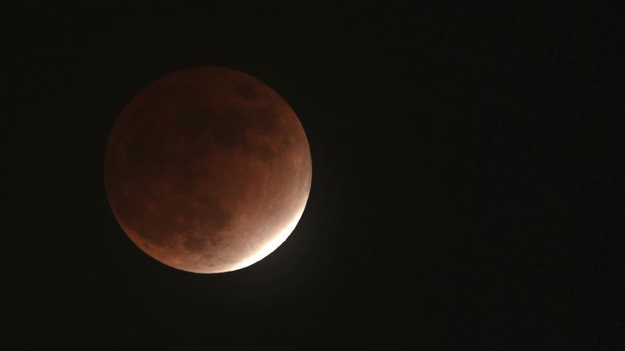 Bayangan bumi menutupi bulan saat gerhana bulan parsial di Yokohama, dekat Tokyo, Jumat (19/11/2021). (AP/Eugene Hoshiko)