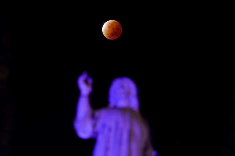Gerhana bulan parsial atau Bulan darah di atas Catania di Piazza Universita, Italia Orang-orang menyaksikan gerhana bulan parsial di atas Catania di Piazza Universita, Italia (19/11/2021). (REUTERS/Antonio Parrinello)