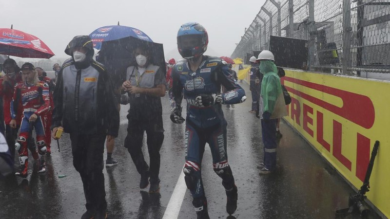 Seorang mekanik mendorong sepeda motor ke paddock di tengah hujan lebat menjelang Race 1 Kejuaraan Dunia Superbike di Sirkuit Internasional Mandalika di Mandalika, Pulau Lombok, Indonesia, Sabtu, 20 November 2021. Kondisi cuaca pada hari Sabtu menyebabkan penundaan Race 1 hingga Minggu, 21 November. (AP Photo/Achmad Ibrahim)