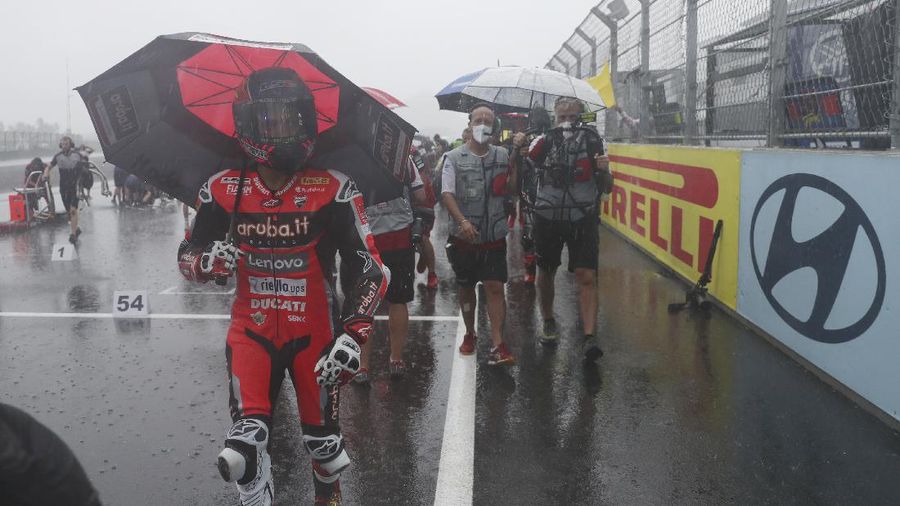 Seorang mekanik mendorong sepeda motor ke paddock di tengah hujan lebat menjelang Race 1 Kejuaraan Dunia Superbike di Sirkuit Internasional Mandalika di Mandalika, Pulau Lombok, Indonesia, Sabtu, 20 November 2021. Kondisi cuaca pada hari Sabtu menyebabkan penundaan Race 1 hingga Minggu, 21 November. (AP Photo/Achmad Ibrahim)