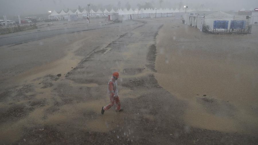 Seorang mekanik mendorong sepeda motor ke paddock di tengah hujan lebat menjelang Race 1 Kejuaraan Dunia Superbike di Sirkuit Internasional Mandalika di Mandalika, Pulau Lombok, Indonesia, Sabtu, 20 November 2021. Kondisi cuaca pada hari Sabtu menyebabkan penundaan Race 1 hingga Minggu, 21 November. (AP Photo/Achmad Ibrahim)