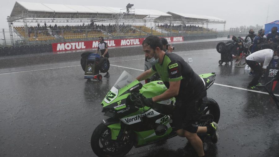 Seorang mekanik mendorong sepeda motor ke paddock di tengah hujan lebat menjelang Race 1 Kejuaraan Dunia Superbike di Sirkuit Internasional Mandalika di Mandalika, Pulau Lombok, Indonesia, Sabtu, 20 November 2021. Kondisi cuaca pada hari Sabtu menyebabkan penundaan Race 1 hingga Minggu, 21 November. (AP Photo/Achmad Ibrahim)