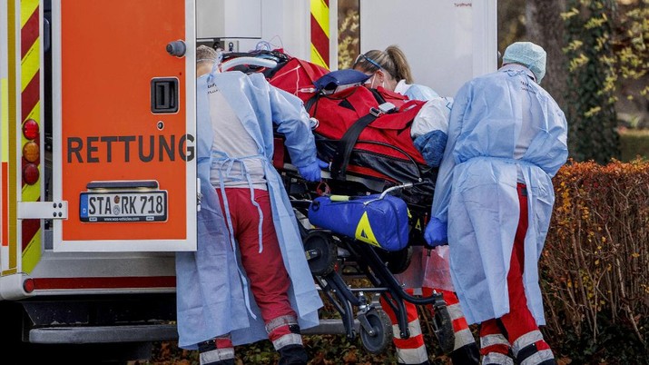 Rescue workers load a Covid 19 intensive care patient from an air rescue helicopter onto an ambulance vehicle at a sports field in Herrsching, Germany, Friday, Nov.19, 2021. The Covid 19 intensive care patient is transferred from the hospital in Trostberg to a private clinic in Herrsching am Ammersee. (Matthias Balk/dpa via AP)
