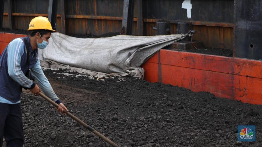 Pekerja membersihkan sisa-sisa batu bara yang berada di luar kapal tongkang pada saat bongkar muat di Pelabuhan Tanjung Priok, Jakarta, Senin (22/11/2021). Pemerintah Indonesia berambisi untuk mengurangi besar-besaran konsumsi batu bara di dalam negeri, bahkan tak mustahil bila meninggalkannya sama sekali. Hal ini tak lain demi mencapai target netral karbon pada 2060 atau lebih cepat, seperti yang dikampanyekan banyak negara di dunia. (CNBC Indonesia/ Tri Susilo)