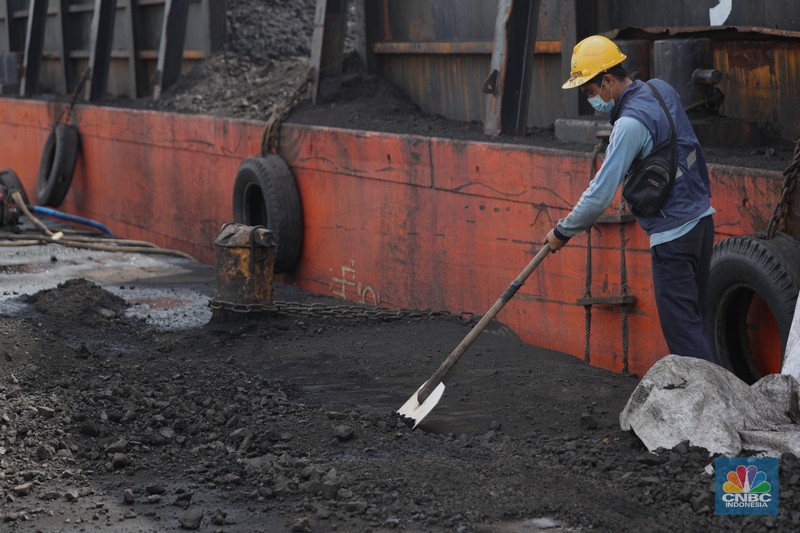 Pekerja membersihkan sisa-sisa batu bara yang berada di luar kapal tongkang pada saat bongkar muat di Pelabuhan Tanjung Priok, Jakarta, Senin (22/11/2021). Pemerintah Indonesia berambisi untuk mengurangi besar-besaran konsumsi batu bara di dalam negeri, bahkan tak mustahil bila meninggalkannya sama sekali. Hal ini tak lain demi mencapai target netral karbon pada 2060 atau lebih cepat, seperti yang dikampanyekan banyak negara di dunia. (CNBC Indonesia/ Tri Susilo)