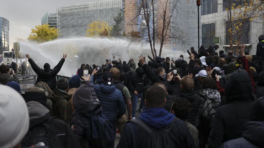 Riot police uses a water canon against protestors during a demonstration against the reinforced measures of the Belgium government to counter the latest spike of the coronavirus in Brussels, Belgium, Sunday, Nov. 21, 2021. Many among them also protested against the strong advice to get vaccinated and any moves to impose mandatory shots. (AP Photo/Olivier Matthys)