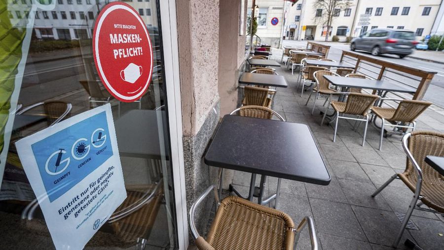 A sign indicating COVID-19 restrictions of mandatory masks hangs on a post along a pedestrian street in Flensburg, Germany, Wednesday, Nov. 24, 2021.(Roland Weihrauch/dpa via AP)