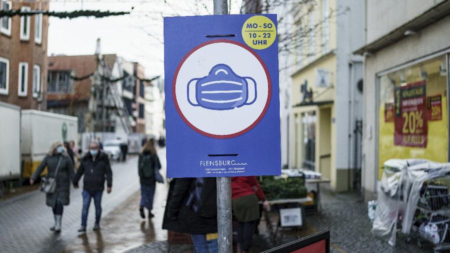A sign indicating COVID-19 restrictions of mandatory masks hangs on a post along a pedestrian street in Flensburg, Germany, Wednesday, Nov. 24, 2021.(Roland Weihrauch/dpa via AP)