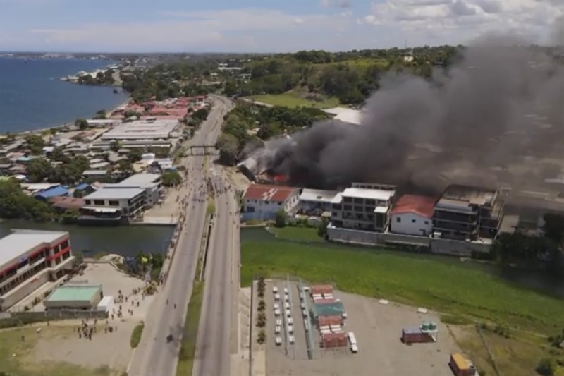 Kerusuhan di Solomon Asap mengepul dari gedung-gedung yang terbakar selama protes di ibu kota Honiara, Kepulauan Solomon, Kamis (25/11/2021). (Australian Broadcasting Corporation via AP)
