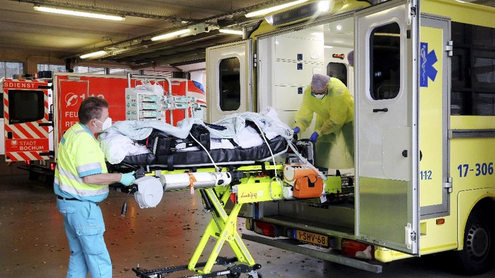 The crew of a Dutch ambulance brings a COVID-19 19 patient from Rotterdam to BG University Hospital Bochum, Germany, Tuesday, Nov. 23, 2021. The country is this week expected to pass 100,000 coronavirus-related deaths since the start of the pandemic. Hospitals warn that ICU capacities are nearly exhausted, with some patients having to be transferred to clinics in other parts of Germany. (Roland Weihrauch/dpa via AP)