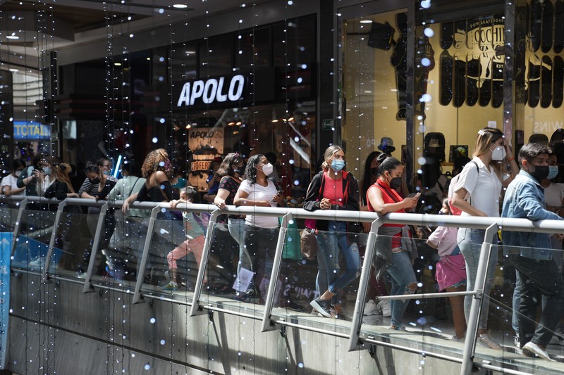 Shoppers, wearing protective face masks, line up to enter the Sambil Mall, in Caracas, Venezuela, Friday, Nov. 26, 2021.  At malls and few stores, Venezuelans are taking the opportunity to buy clothes and other articles with generous Black Friday discounts. (AP Photo/Ariana Cubillos)