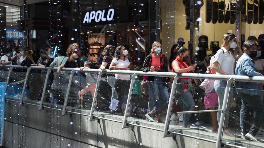 Shoppers, wearing protective face masks, line up to enter the Sambil Mall, in Caracas, Venezuela, Friday, Nov. 26, 2021.  At malls and few stores, Venezuelans are taking the opportunity to buy clothes and other articles with generous Black Friday discounts. (AP Photo/Ariana Cubillos)