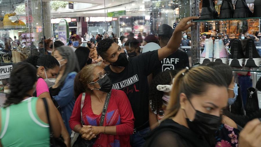 Shoppers, wearing protective face masks, line up to enter the Sambil Mall, in Caracas, Venezuela, Friday, Nov. 26, 2021.  At malls and few stores, Venezuelans are taking the opportunity to buy clothes and other articles with generous Black Friday discounts. (AP Photo/Ariana Cubillos)
