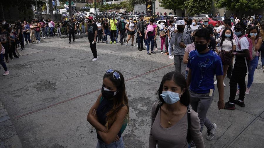 Shoppers, wearing protective face masks, line up to enter the Sambil Mall, in Caracas, Venezuela, Friday, Nov. 26, 2021.  At malls and few stores, Venezuelans are taking the opportunity to buy clothes and other articles with generous Black Friday discounts. (AP Photo/Ariana Cubillos)