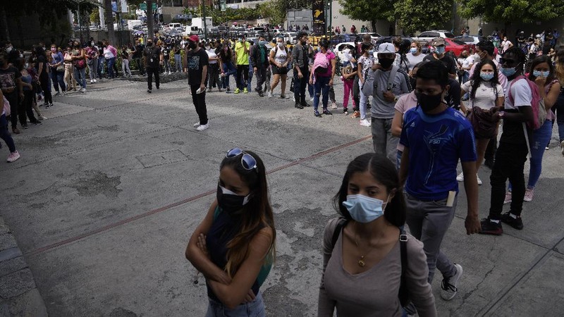 Shoppers, wearing protective face masks, line up to enter the Sambil Mall, in Caracas, Venezuela, Friday, Nov. 26, 2021.  At malls and few stores, Venezuelans are taking the opportunity to buy clothes and other articles with generous Black Friday discounts. (AP Photo/Ariana Cubillos)